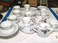 Full tea and cake set displayed including teapot, sugar bowl, cups, saucers, small plates, and serving trays. Bamboo pattern on porcelain.