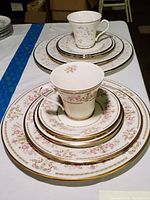 Overview of the pink floral and gold decorative dinnerware set with stacked plates and a teacup and saucer on top.