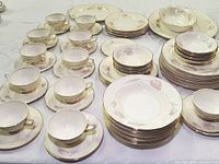 Full view of the set featuring multiple teacups, saucers, stacked bowls, and dinner plates arranged on a table, showing the floral Georgian pattern.