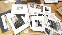 Overview photo showing multiple black and white woodcut and stone engraving prints arranged on a wooden surface, some shows pears and abstract shapes