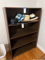 Full view of composite four shelf storage unit containing five hats on the second shelf from the top, showing overall condition and size.