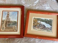 Two framed prints side by side showing the Golden Gate Bridge and a cabin scene.