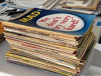 Stack of roughly 40 Mad Magazines from the 1960s with colorful covers and visible wear.