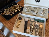 Photo of gold-tone chain necklace with matching crescent moon and circle earrings, and white box containing eight wristwatches of various brands and styles.