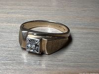 Front view showing square bezel-set princess cut diamond and brushed finish shoulders