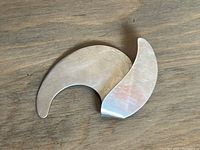 Front view of a modern sterling silver abstract brooch with two curved overlapping shapes.