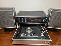 Front view of vintage Panasonic stereo with lift-up panel revealing the turntable and two speakers on each side.