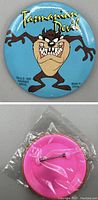 Front and back view of 1995 Warner Bros Tazmanian Devil button pin; front shows cartoon character on blue background, back is pink with pin clasp, sealed in plastic.
