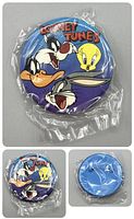 Front view of the round Looney Tunes button pin displaying Bugs Bunny, Tweety, Daffy Duck and Sylvester on a blue background with Looney Tunes text at top. Sealed in plastic wrap.