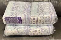Two large sealed packs of Luvs diapers, size 6, stacked on a dark gray couch.