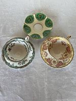 Set of two Aynsley teacups with their matching floral saucers plus one extra green floral saucer