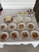 Full set displayed on white cloth including plates, flower ornaments, candle holders, salt & pepper shakers