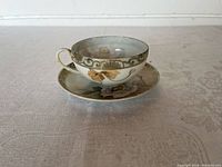 Side view of the hand-painted Nippon porcelain teacup and saucer showing floral and gold designs
