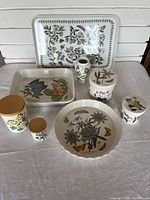 Overview of 12 botanical design pieces including platter, lasagna dish, pie plate, vase, and 4 jars with lids