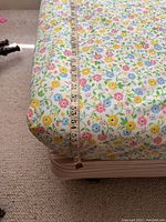 Close-up photo showing floral patterned mattress with measuring tape indicating thickness about 8-10 inches.