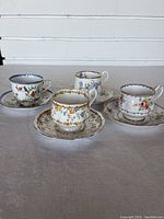 Four Royal Albert teacups and saucers on a table showing distinct floral patterns and gold trim.