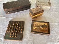 Overview of the four main items: two polished mother of pearl trinket boxes, antique peg game, and sharpening stone.