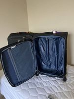 Open view of one black Ricardo suitcase showing interior blue lining and zippered mesh storage panel.