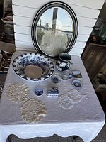 Photo showing the full collection on a white cloth, including ceramics, glassware, doilies and framed print.