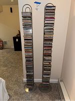 Photo of two tall slim metal CD racks fully loaded with mixed music CDs.