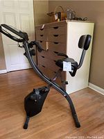 Full side view of the foldable Slim Cycle exercise bike showing seat with backrest and pedals.