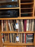 Wooden shelving unit with turntable and receiver on top, lower shelves filled with vinyl records