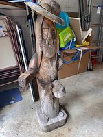 Front view of the wooden sculpture showing detailed carving and large hat