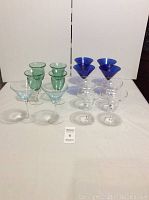 Front view of entire set showing 4 green bubble glasses, 4 dark blue martini glasses, 2 light blue martini glasses and 4 clear margarita glasses