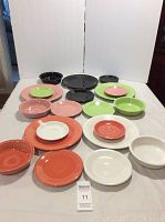 Photo showing 5 place settings of Fiesta Ware including plates, salad plates, bowls, and small dishes in various colors such as red, pink, green, white, and black.