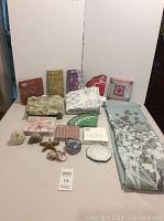 Wide shot showing shower curtains rolled up and paper napkin packs arranged behind small decorative boxes and figurines on table.