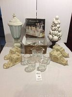 Initial overview of all items showing barware sets, resin sconces, ceramic topiary, and glass urn with resin base and lid on table.
