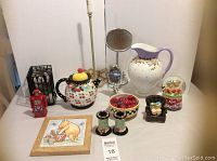 Full lot showing Mary Englebreit ceramics, the raccoon stuffed animal in cage, mirrors, red robot, Winnie the Pooh frame, and bowl of cherries