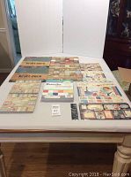 Photo showing various scrapbook paper packs including large 12x12 sized sheets laid flat on table showing diverse designs and themes.