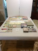 Full spread of assorted scrapbook and crafting supplies arranged on a table including paper pads, kits and embellishments