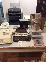 Overview of the lot showing HP LaserJet 3015, Lexmark X2350, Cuisinart food processor with accessories and covers