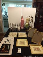 Full lot showing framed pictures, bottles of vase filler sand, decorative ceramic container, light green pendant lamp, and gold metal easel.
