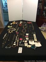 Full view of the assortment of necklaces, bracelets, earrings, and watches laid out on a black cloth