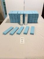 Photo showing 86 light blue rectangular necklace and jewelry boxes arranged in stacks on a table, with five boxes placed in front to show different sizes.