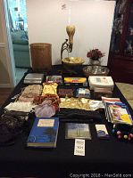 Photo showing Audiovox portable DVD player, yellow decorative bowl with loose vase, dip n chip bowl, flower arrangement, Scotch disc cleaner, and various gift bags and books on table.