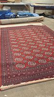 Full view of large red patterned area rug laid flat showing design and size.