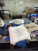 Bundles of natural burlap sacks tied with white string on table with other bags.