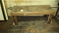 Vintage wooden bench, viewed from the front showing solid construction and wear.
