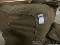 Large bundle of folded or rolled canvas bags stacked together with sackcloth material.