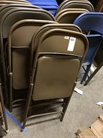 Group of fourteen metal folding chairs, majority brown with some blue chairs, stacked together revealing overall condition and color variety.