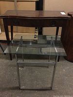 Both tables side-by-side showing the foyer table behind the glass-top side table, highlighting the drawer and metal legs.