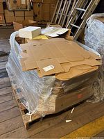 Pallet of flat-packed brown cardboard gift boxes wrapped in plastic.