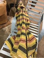 Patio lounge chair with multi-colored striped umbrella folded and placed on the chair.