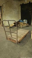 Full view of the vintage dolly cart showing wooden platform and metal frame with handle bars and wheels.
