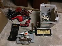 Overview of lot items including Black & Decker finishing sander, Hyper Tough drill, socket wrench set, hand vacuum, C clamp, mallet, and plastic bin with accessories.