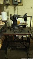 Full view of vintage Singer sewing machine on wooden table with metal frame and a spool of white thread.